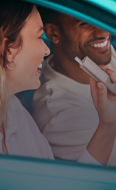 An IQOS device held by one person and a smartphone held by another person.